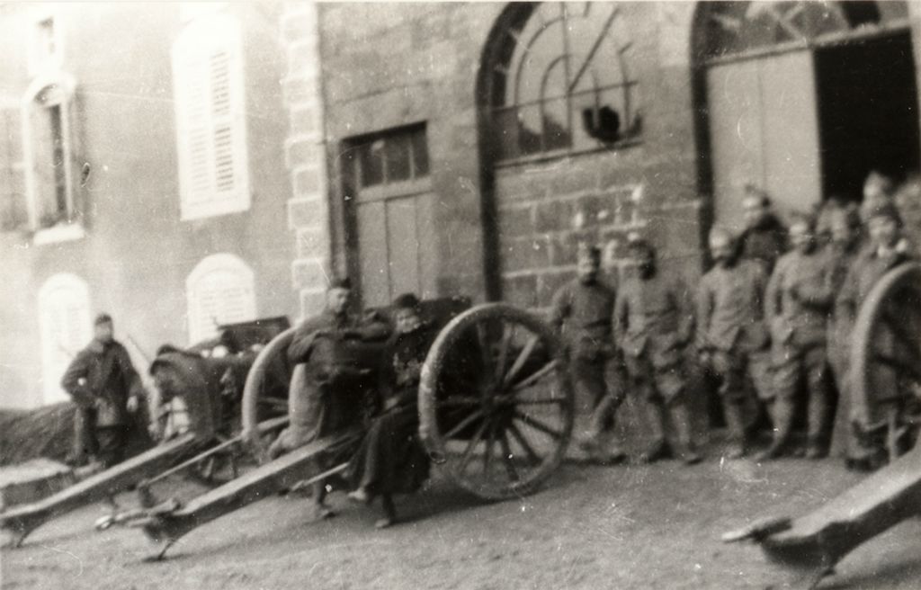 Agnes Swift sitting on axel of artillery piece, 1917, possibly in Contrexeville