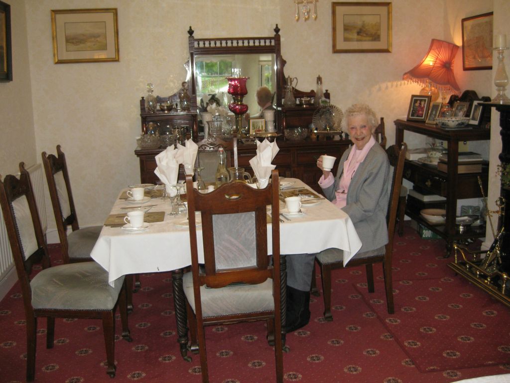 Mother seated in the breakfast room at Clareview House, waiting for her daughters to arrive.
