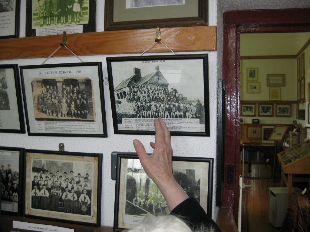 Sister DeLourdes points to photographs of classes of children who attended the Kiltartan School.
